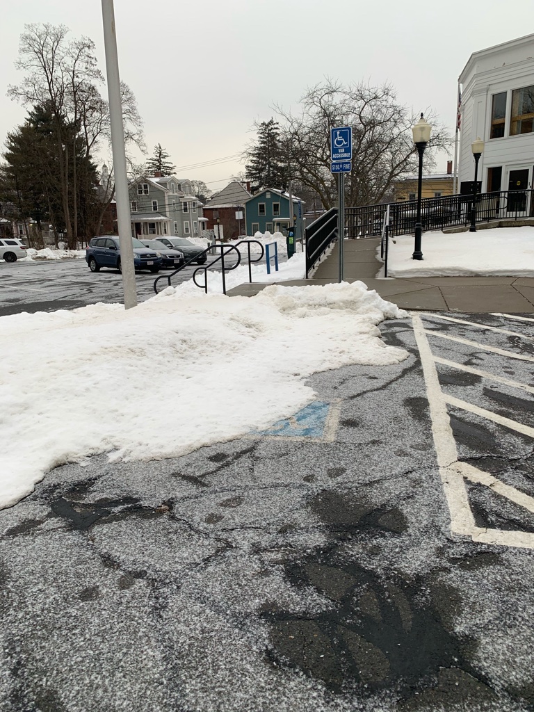 Photo of a snow covered handicap parking spot.